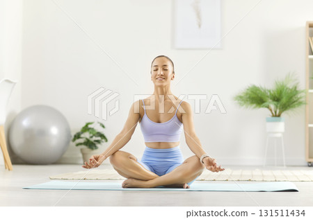 Young Asian woman practicing yoga at home, doing meditation, relaxing and relieving stress Young Asian woman practicing yoga at home, doing meditation, relaxing and relieving stress 131511434