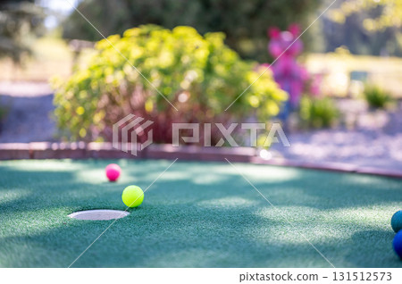 Colorful golf balls on a mini golf course with a vibrant background in sunny weather 131512573