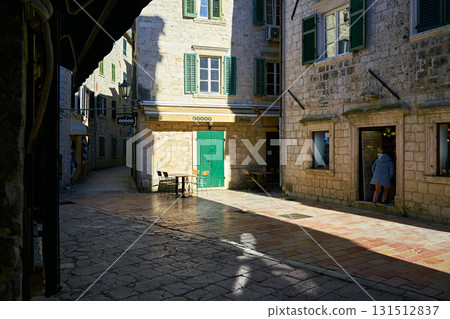 Sunny Old Town Street Corner with Historic Stone Buildings, Green Shutters, and Pedestrian Sunny Old Town Street Corner with Historic Stone Buildings, Green Shutters, and Pedestrian 131512837
