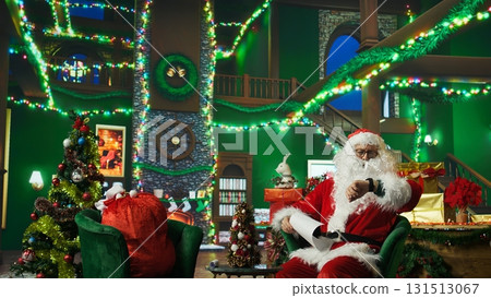Person in Christmas costume alerted after dozing off and running late on delivering gifts to children. Santa Claus waking up after falling asleep on armchair while reading letters from kids, camera A Person in Christmas costume alerted after dozing off and running late on delivering gifts to children. Santa Claus waking up after falling asleep on armchair while reading letters from kids, camera A 131513067