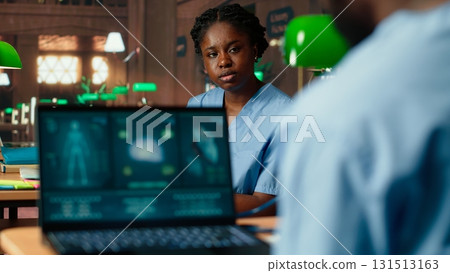 Med school student takes personal notes from anatomy research papers, studying healthcare methods for a medical career. Male scholar using books from the campus databases. Camera B. Med school student takes personal notes from anatomy research papers, studying healthcare methods for a medical career. Male scholar using books from the campus databases. Camera B. 131513163