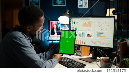 Young guy examining funds for a program and holding tablet with mockup, studying finances and accounting management on a software. Male specialist doing remote work for a startup. Camera A. 131513175