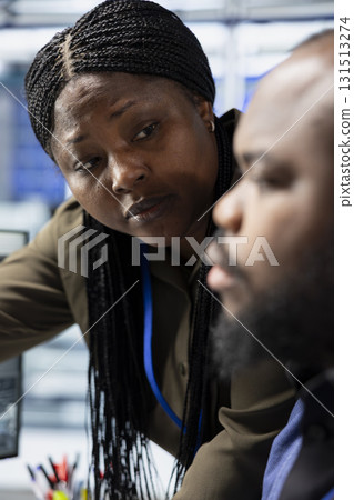 Black engineering specialists gather in a solar panel facility to monitor workflow, showcasing corporate leadership and teamwork in the renewable energy sector. Sustainable development. 131513274