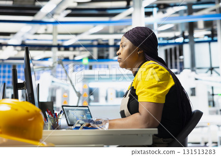 Photovoltaics factory supervisor using computer for a test inspection, finetuning the production process. Woman improving solar panel configurations for eco friendly renewable energy. Photovoltaics factory supervisor using computer for a test inspection, finetuning the production process. Woman improving solar panel configurations for eco friendly renewable energy. 131513283