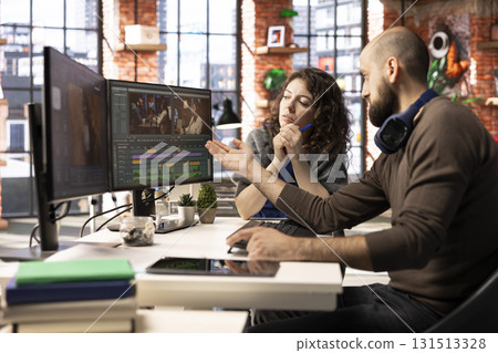 Man and woman filmmakers editing a video shoot in post production, using a modern tech setup and editing software for a creative video project. Modern workspace with dual monitors. 131513328