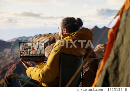Entrepreneur uses high speed internet connection on mountain top, enjoying the video call with a scenic landscape. Young hiker having an internet dependency and being workaholic. Entrepreneur uses high speed internet connection on mountain top, enjoying the video call with a scenic landscape. Young hiker having an internet dependency and being workaholic. 131513346