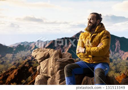 Hiker traveler pauses to admire the panoramic mountain scenery on the hill top, endless sky and rocky peaks creating a breathtaking backdrop for mental clarity. Adventure seeker outdoors. Hiker traveler pauses to admire the panoramic mountain scenery on the hill top, endless sky and rocky peaks creating a breathtaking backdrop for mental clarity. Adventure seeker outdoors. 131513349