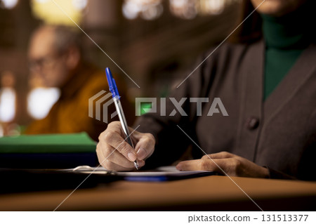 Adult woman studies in a library and transcribing a lecture, concentrating on class notes and showing her determination to researching. Scholar preparing for her college thesis. Close up. Adult woman studies in a library and transcribing a lecture, concentrating on class notes and showing her determination to researching. Scholar preparing for her college thesis. Close up. 131513377