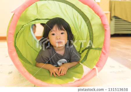 Toddler girl playing on tunnel play equipment Toddler girl playing on tunnel play equipment 131513638