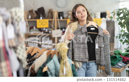 Young woman chooses jacket in clothing store Young woman chooses jacket in clothing store 131514882