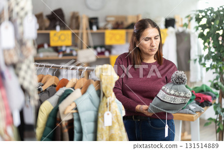 Latina woman chooses demi-season hat in clothing store. Latina woman chooses demi-season hat in clothing store. 131514889