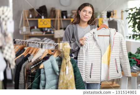 Young girl choosing down jacket in clothing store 131514901