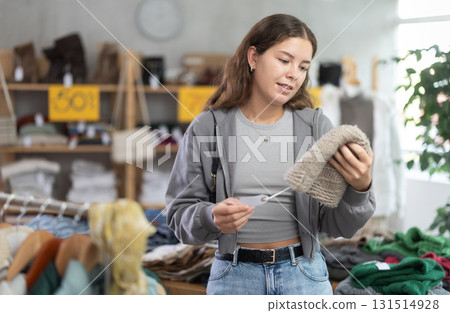 Happy girl chooses hat in modern clothing store 131514928