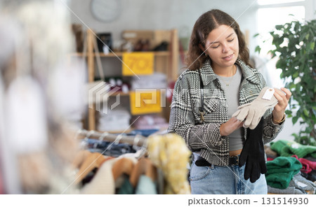 During November sales, young woman choose and buy gloves 131514930