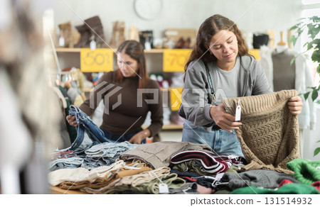 Two selective women choosing pantaloons and pullovers in clothing store Two selective women choosing pantaloons and pullovers in clothing store 131514932