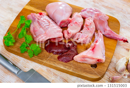 Chopped rabbit with onion, garlic and spices on kitchen board with knife 131515003