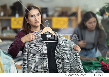 Adult woman chooses jacket in clothing store Adult woman chooses jacket in clothing store 131515060