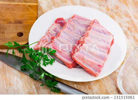 Racks of fresh raw pork ribs on plate with parsley and knife 131515061