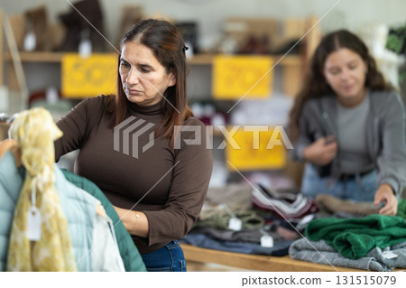 Selective Latina woman choosing something for autumn-winter in clothing store Selective Latina woman choosing something for autumn-winter in clothing store 131515079