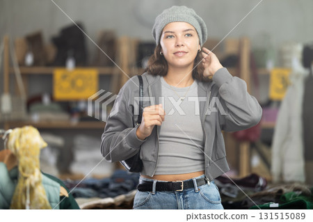 During November sales, young woman choose and try on hat, view reflection in mirror. 131515089