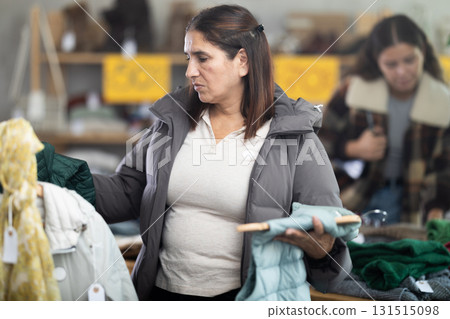 Adult woman chooses vest in clothing store Adult woman chooses vest in clothing store 131515098