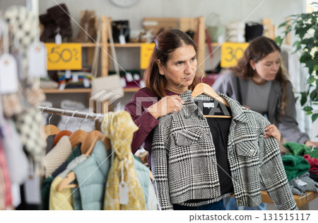 Selective Latina woman choosing something for autumn-winter in clothing store Selective Latina woman choosing something for autumn-winter in clothing store 131515117