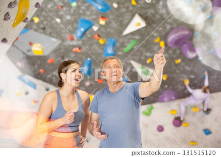 Trainer giving instructions to man on wall climbing at bouldering gym indoor Trainer giving instructions to man on wall climbing at bouldering gym indoor 131515120