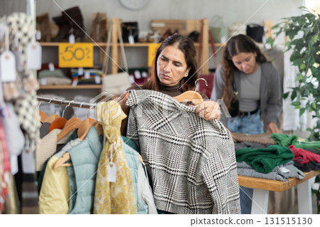 Adult woman chooses jacket in clothing store Adult woman chooses jacket in clothing store 131515130