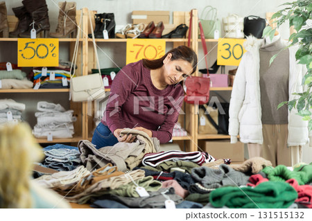 Female latina shopper chooses trousers in modern clothing store 131515132