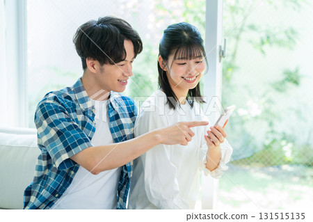 couple looking at smartphone in living room couple looking at smartphone in living room 131515135