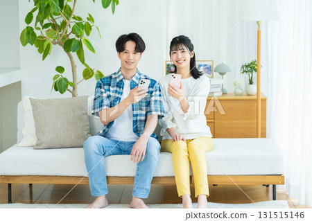 夫婦在客廳裡看智能手機 夫婦在客廳裡看智能手機 131515146