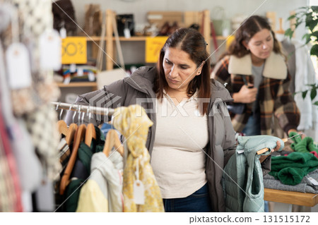 Adult woman chooses vest in clothing store Adult woman chooses vest in clothing store 131515172