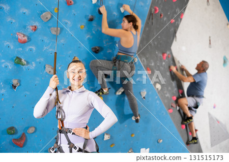 Sporty woman equipped with climbing safety rope standing in bouldering center 131515173