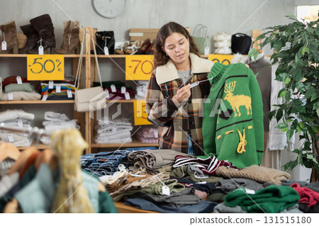Selective young woman choosing jersey in clothing store Selective young woman choosing jersey in clothing store 131515180