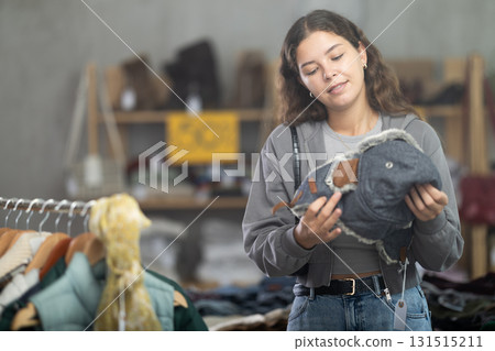 Young woman choosing fur hat in clothing store Young woman choosing fur hat in clothing store 131515211