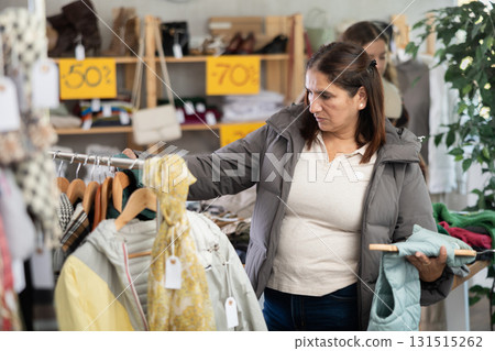 Adult woman chooses vest in clothing store Adult woman chooses vest in clothing store 131515262