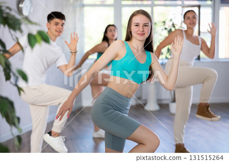 Smiling teenage girl practicing vigorous dance with group of friends Smiling teenage girl practicing vigorous dance with group of friends 131515264