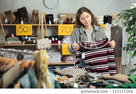 Girl chooses warm pullover, cardigan or sweater in clothing store Girl chooses warm pullover, cardigan or sweater in clothing store 131515268