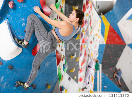 Concentrated young girl climbing on bouldering wall in gym Concentrated young girl climbing on bouldering wall in gym 131515270