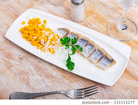 Pieces of herring served with corn and onions. Appetizer fish on table Pieces of herring served with corn and onions. Appetizer fish on table 131515277