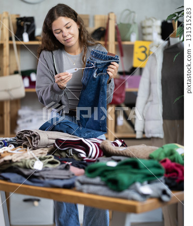 Female shopper chooses a jeans trousers in clothing store Female shopper chooses a jeans trousers in clothing store 131515283