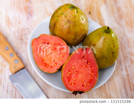 Whole and halved tropical apple guavas on wooden background 131515286