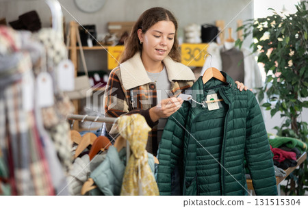 During November sales, young woman choose and buy down coat During November sales, young woman choose and buy down coat 131515304