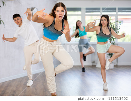 Girl teen perform choreographic exercise and teach energetic mobile social dance groove with friends 131515402
