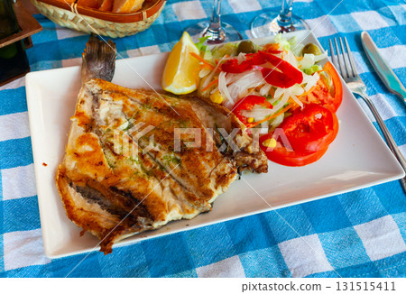 Fried dorada dressed with pesto served with vegetable garnish and lemon Fried dorada dressed with pesto served with vegetable garnish and lemon 131515411