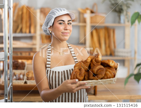 Young woman seller with basket of croissants 131515416