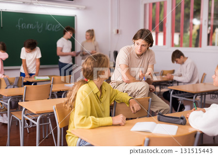 Teenagers resting and talking during recess in classroom Teenagers resting and talking during recess in classroom 131515443
