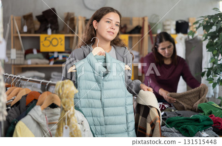 During November sales, young woman choose vest, other client in background During November sales, young woman choose vest, other client in background 131515448