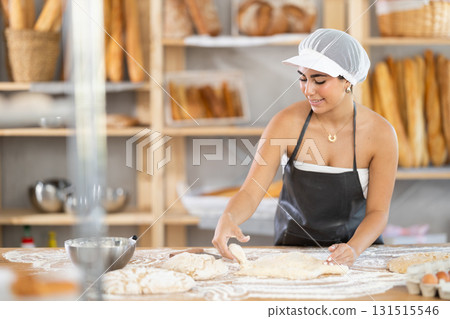 Young woman baker kneads the dough in bakery Young woman baker kneads the dough in bakery 131515546