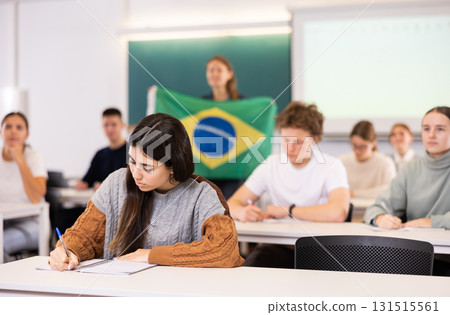 Female teacher tells her classmates about the country of Brazil, holding a flag in hands 131515561